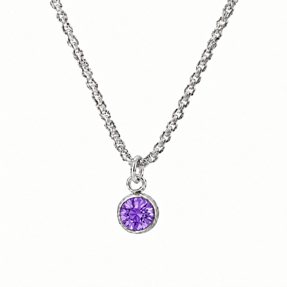 Srebrzysty naszyjnik z okrągłą fioletową cyrkonią w zbliżeniu na białym tle