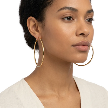 Duże złote kolczyki koła 70 mm na modelce na białym tle