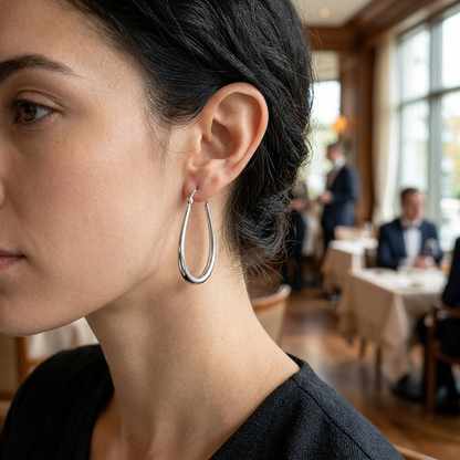 Srebrny kolczyk w kształcie kropli na modelce w restauracji